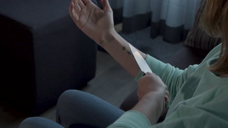 close up of trembling woman pointing knife at her wrist, contemplating to commit suicide and throwing knife away