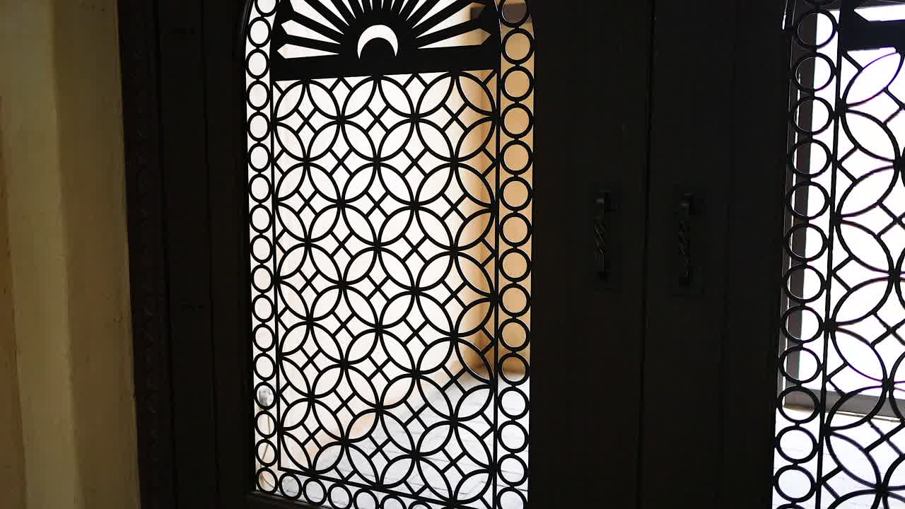 Una porta intarsiata si apre gradualmente, rivelando una vista esterna