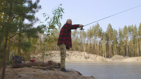 spin fishing of middle-aged man in forest lake man is casting rod and rotating reel during angling relax and enjoy wild nature