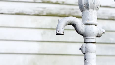 vintage water tap painted white in front of a white striped wall outside