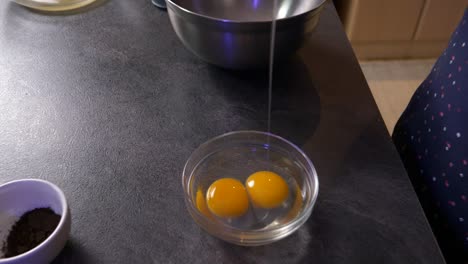 zoom in close up shot of a girl cracking an egg into a glass bowl