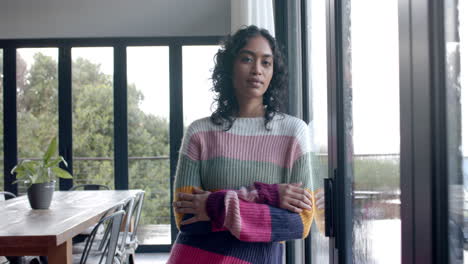 Portrait-of-biracial-woman-leaning-on-window-at-home,-slow-motion