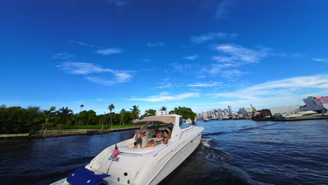 following the motor boat with people resting on. fpv drone follows the yacht sailing by the river crossing the city.