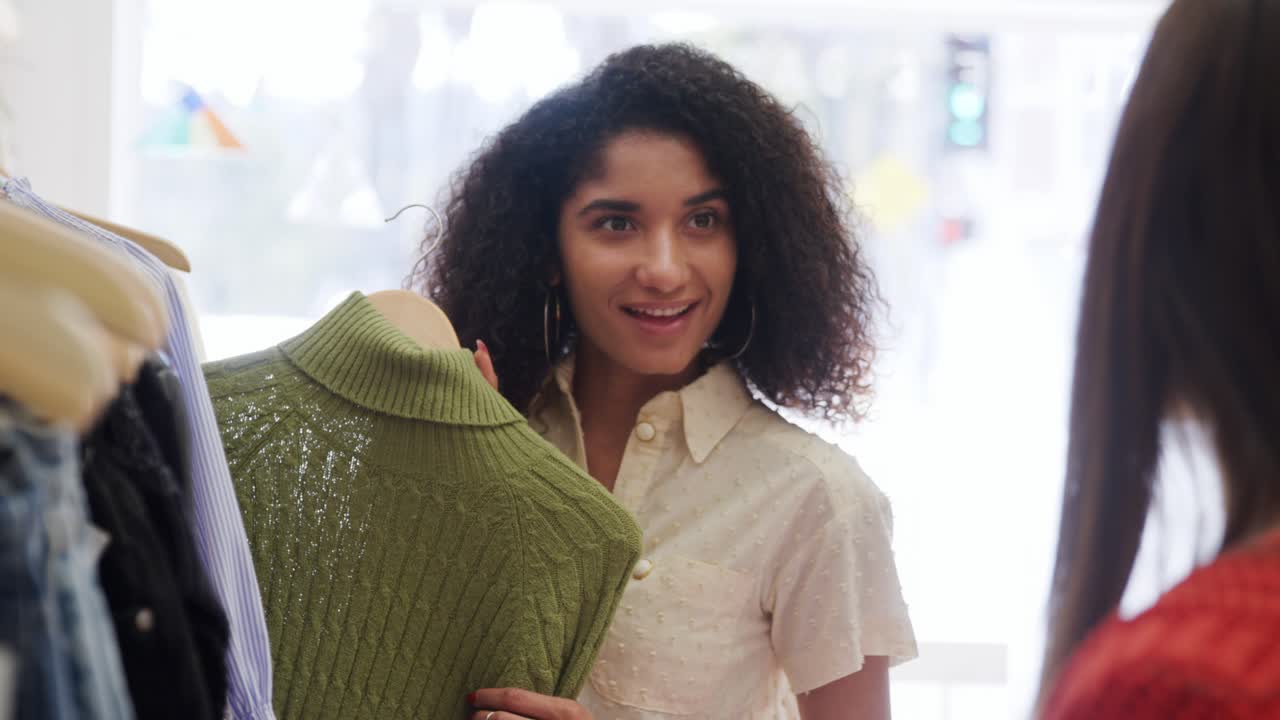 Two Female Friends Shopping In Clothing Store Choosing Jumper From Rack