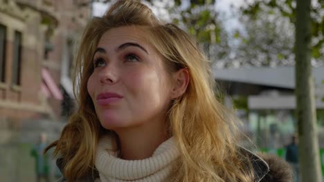 confident beautiful young woman adjusts hair and sweater in the cool morning air