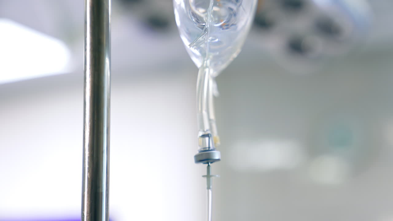 Transparent plastic bag with saline solution hanging on the drop counter. Close up. Blurred backdrop.