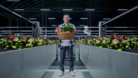 un granjero sonriente sostiene una canasta de verduras frescas en una granja vertical moderna