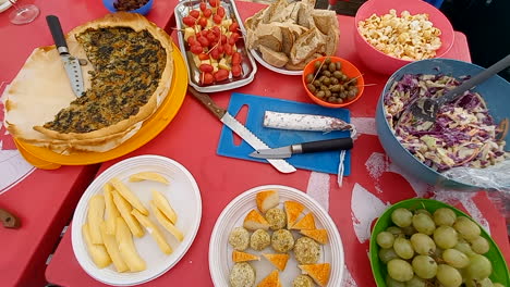 mesa de picnic llena de comida, pizza, queso, fruta, aceitunas, pan y tomates