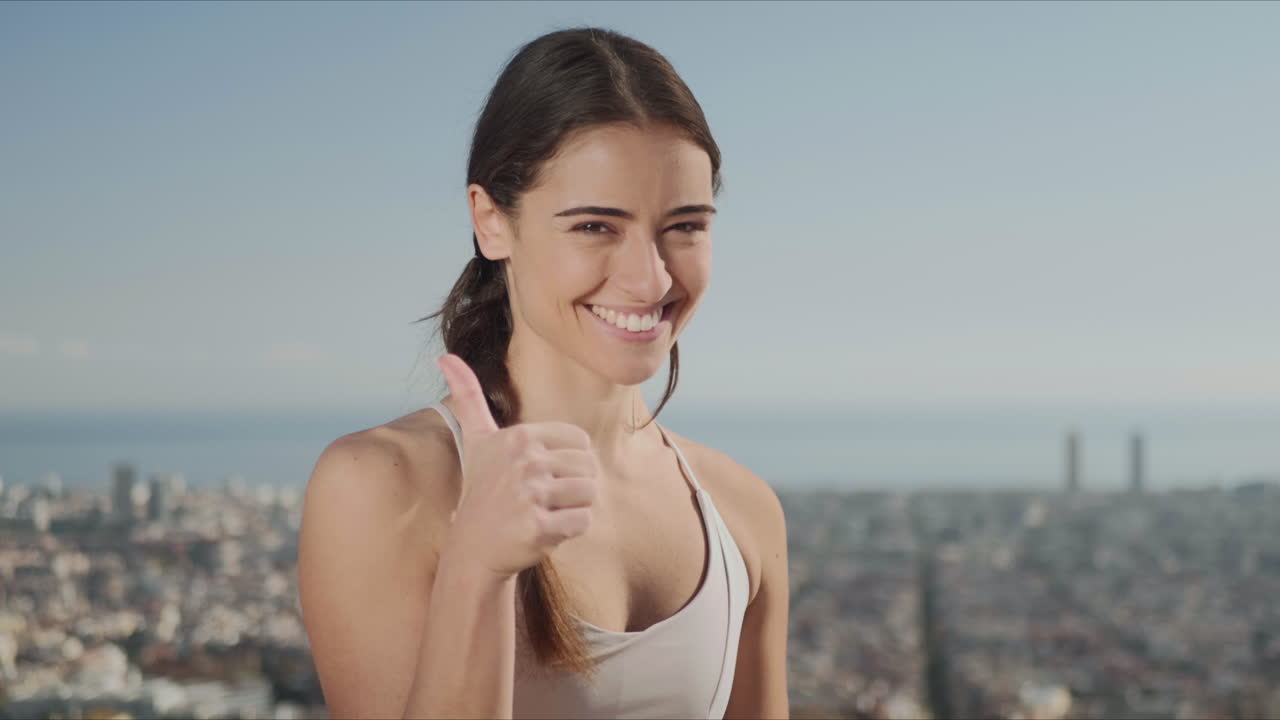 운동선수 는 엄지 손가락 을 올려 표시 하고 있다. 피트니스 여자 는 밖 에서 카메라 를 보고 있다