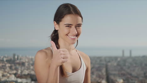 mujer deportista mostrando pulgares hacia arriba señal. mujer de fitness mirando a la cámara afuera