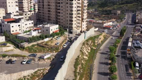 aerial view of a city with a prominent concrete security wall and residential buildings