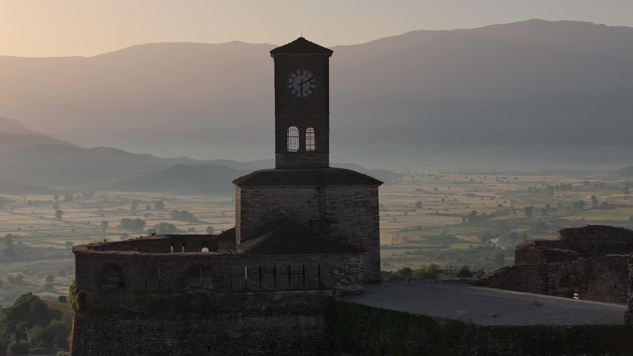 Drone orbiting around clock tower Castle of Gjirokastra, historical landmark in Albania. Morning light.