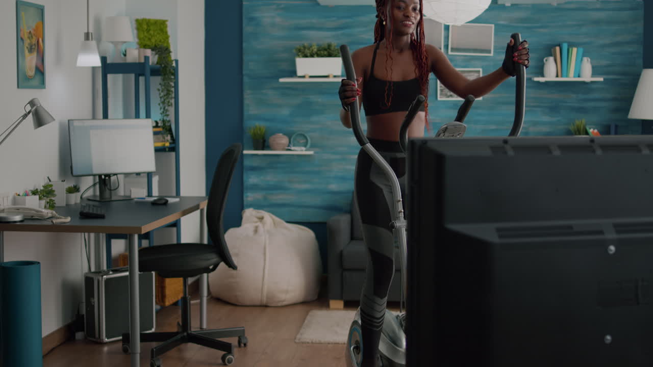 Slim fit woman trainer in sportswear watching fitness video on tv d