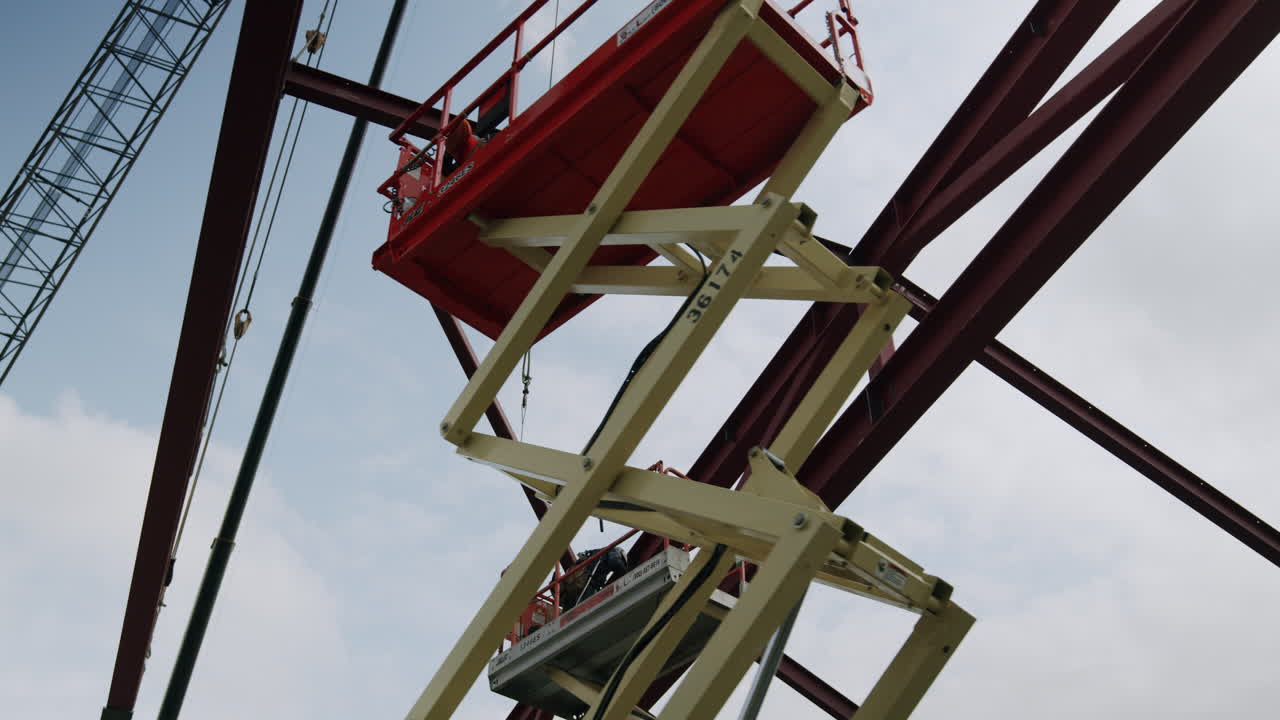 Construction of a steel structure with a worker on a scissor lift