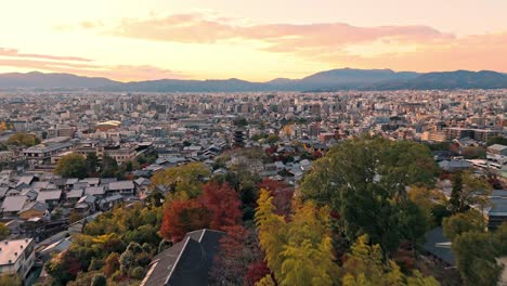 a breathtaking drone shot of hōkan-ji temple (yasaka pagoda) in kyoto at sunset, showcasing the iconic torii gates framed by vibrant autumn foliage.