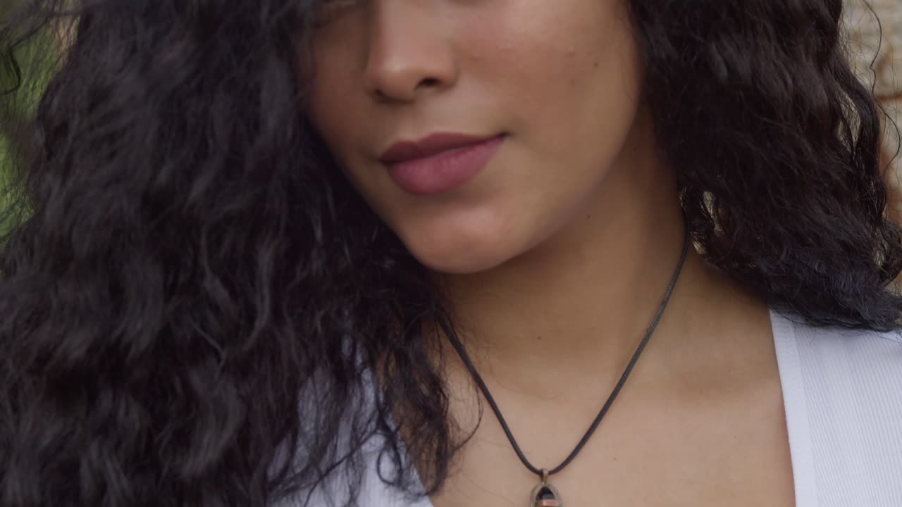 movimiento de cámara ascendente para revelar a una joven de cabello rizado que lleva un collar negro