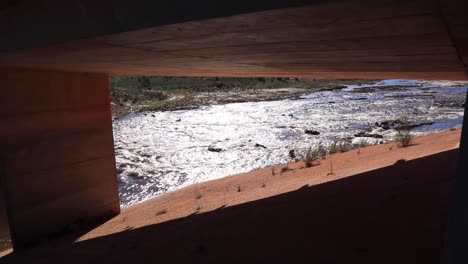 river flowing under bridge in mountains