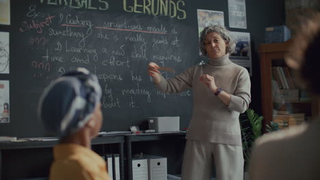 maestra explicando la lección de gramática inglesa a los estudiantes en una escuela de idiomas