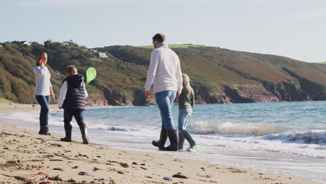 family with fishing nets walking along shoreline of winter beach