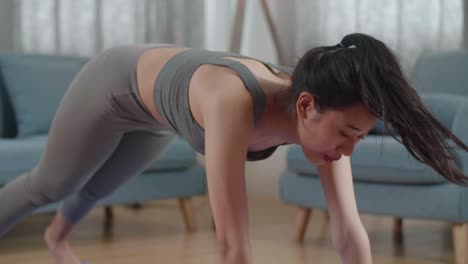 retrato en primer plano de una mujer sana asiática con ropa deportiva entrenando en una alfombra de yoga, haciendo perro mirando hacia arriba durante el entrenamiento en casa