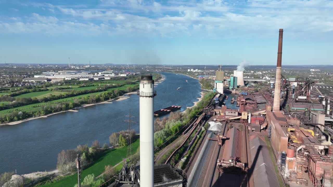 Cokes factory along the rhine river. Industrial production in Germany. Metal industrial chimney. Aerial view.