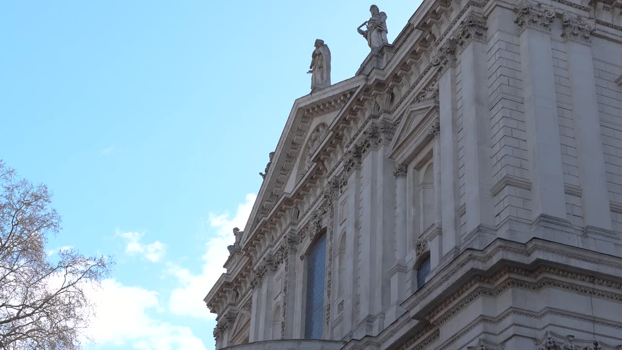 La Cattedrale di St Paul a Londra, che mostra la facciata con statue sul tetto da un'angolazione bassa. Vista diurna con dettagli architettonici e il cielo.
