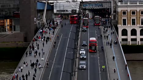 People-walking-over-London-Bridge-alongside-the-Buses,-London,-UNited-Kingdom