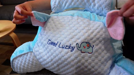 close-up of hands fixing soft elephant ears on a plush cushion—great for kids, decor, or cozy lifestyle content