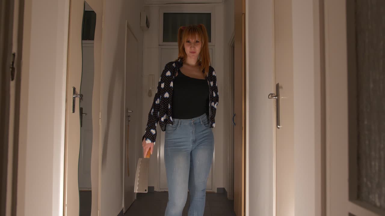 Sexy beautiful and creepy girl standing in the dark hallway showing a cleaver