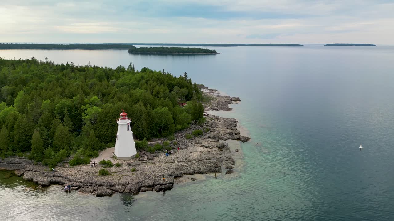 Aerial View of a Lighthouse on a Rocky Coastline with Clear Water and Islands