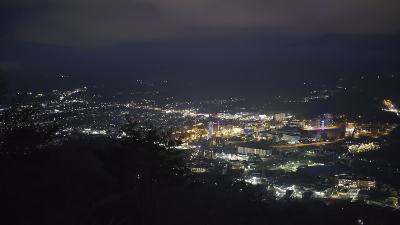 A stunning night view of the Fujikawaguchiko city, where lights twinkle across the landscape. The city skyline contrasts against the dark sky
