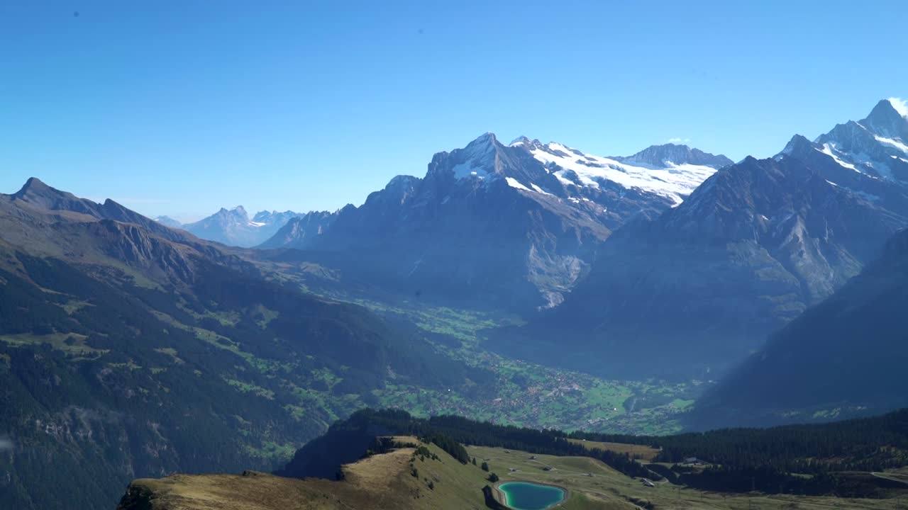 Scenic footage captures majestic rocky mountains of Switzerland, towering against clear blue sky on sunny day, showcasing breathtaking beauty and grandeur of alpine landscape