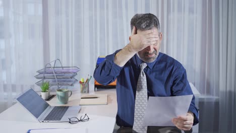 Depressed-mature-businessman-receives-bad-news-on-paperwork-he-is-reading.