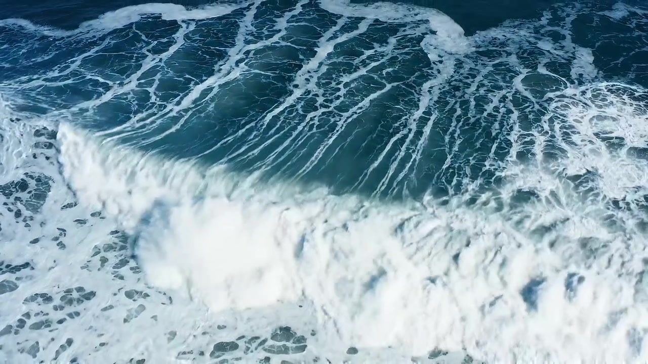 Aerial view of powerful ocean waves breaking with white foam