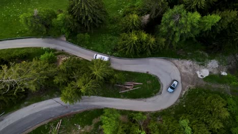 A-passenger-van-drives-down-a-small-road-near-the-town-of-Toblach-in-northeastern-Italy,-an-aerial-tracking-shot