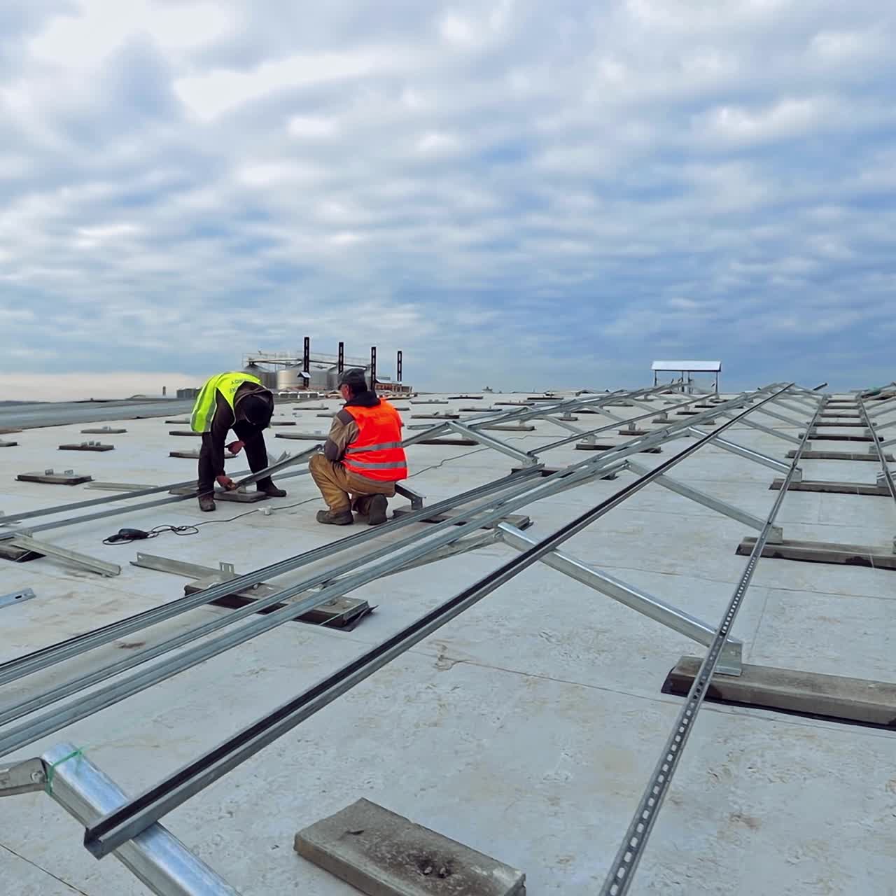 Metal basis for future solar panels on flat roof. Solar panels installation by technicians under the beautiful sky. Building of a new solar farm.