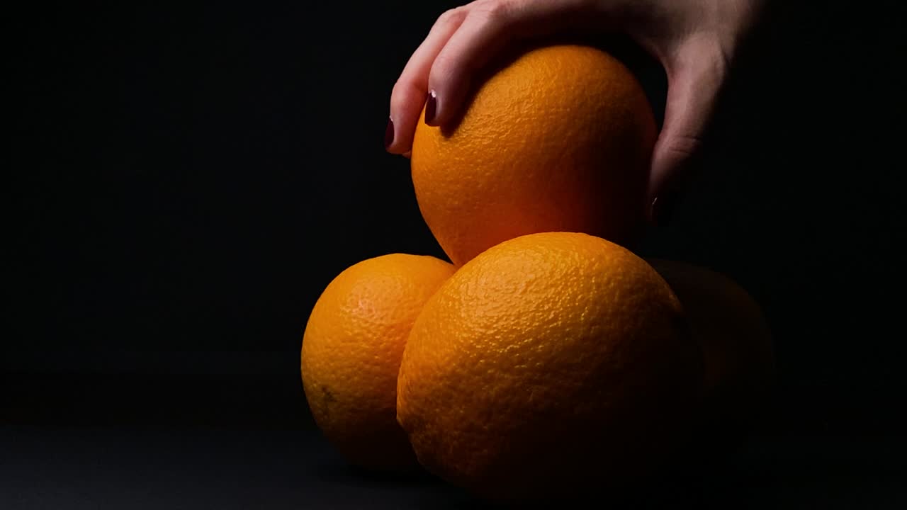 mano de mujer recoger fruta naranja, fondo negro
