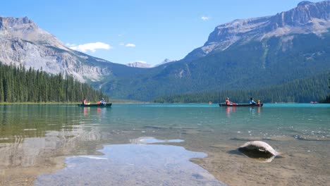 vista del lago azul claro de verano - lago esmeralda con gente mientras canoa en el lago y hermosa cordillera con cielo azul claro en vacaciones de verano en el parque nacional yoho-banff, alberta, canadá