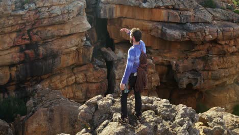 climber shielding his eyes at top of cliff 4k