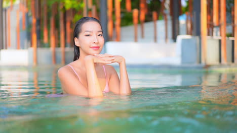 slow-motion of young model thai woman relaxing in a swimming pool water of luxury spa resort in pattaya - face close-up