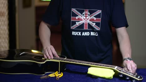 Restringing-and-cleaning-a-beautiful-black-single-cutaway-accoustic-guitar---tensioning-the-strings-by-turning-the-machine-heads-and-removing-the-excess-stings-with-snips