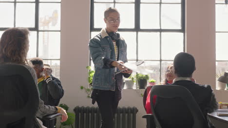 Jóvenes-Empresarios-Se-Reúnen-Con-Un-Líder-De-Equipo-De-Raza-Mixta,-Un-Hombre-Que-Comparte-Documentos,-Discute-Una-Estrategia-De-Marketing,-Intercambia-Ideas,-Planifica-Una-Fecha-Límite-Exitosa-En-Una-Reunión-Informativa-De-Oficinas-Diversas