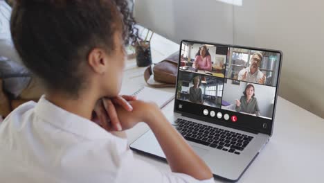 African-american-woman-using-laptop-for-video-call,-with-diverse-business-colleagues-on-screen