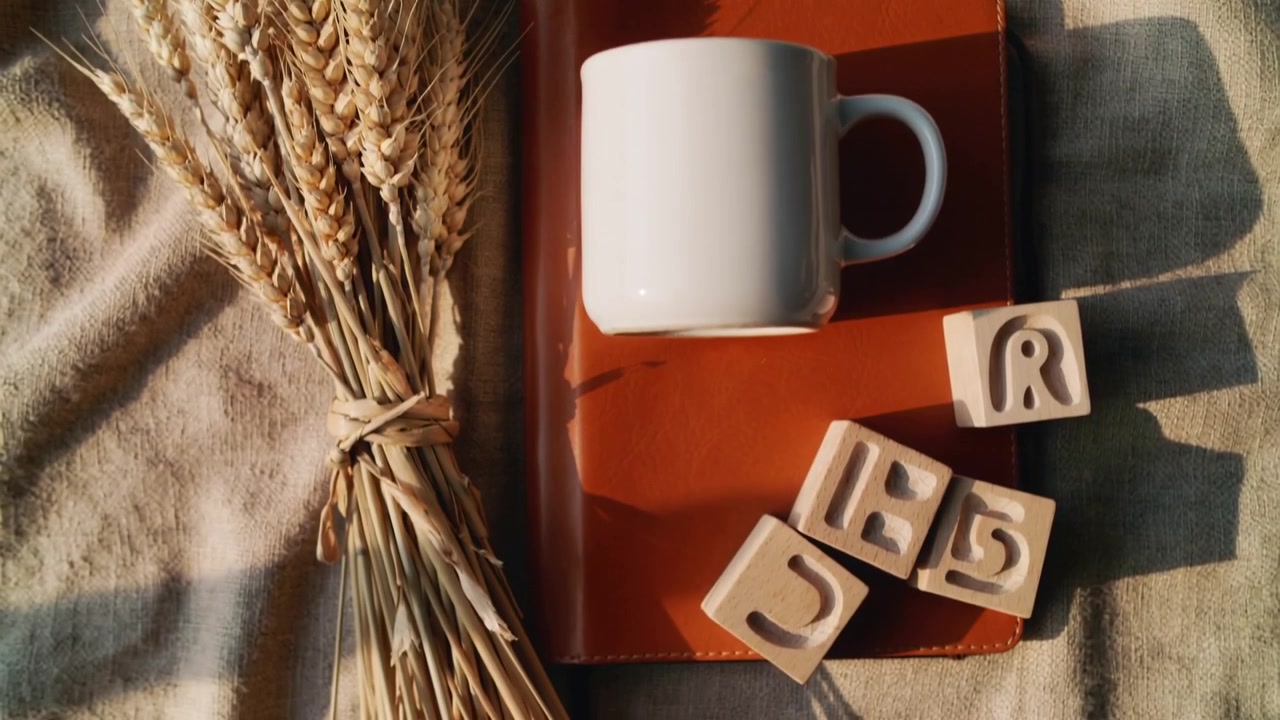 Shifting light nudging wooden blocks sliding toward notebook corner on table, mug and wheat staying