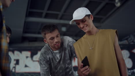 happy teenage friends laughing at something in smartphone outdoors.