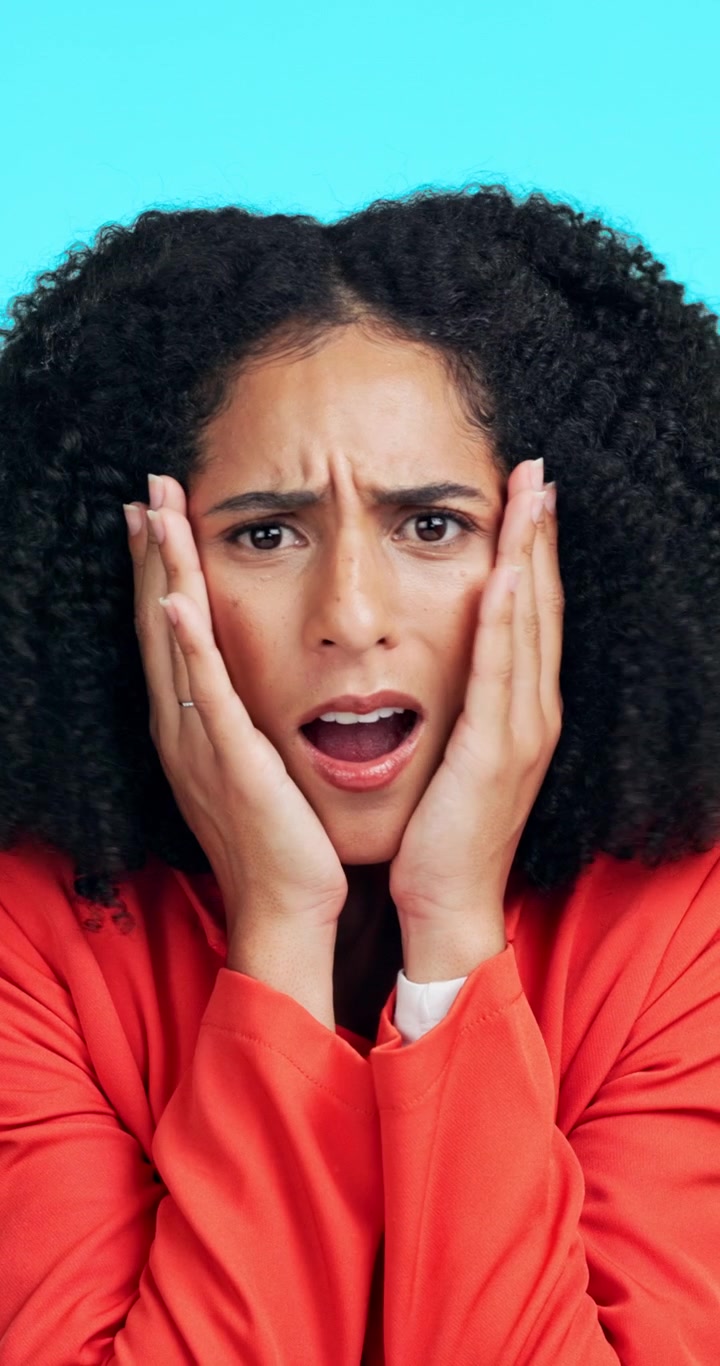 Shocked Woman With Curly Hair Holding Her Face in Surprise