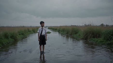 Young student standing on a flooded road during monsoon season, confronting the difficulties of accessing education in remote areas, highlighting the impact of climate change on rural life