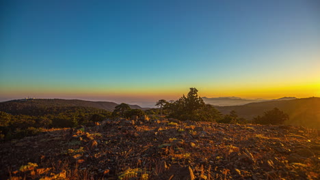 llamarada solar de la puesta del sol sobre picos de montañas rocosas, el viento sopla la hierba