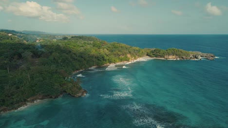 drone shot of hills and sea with waves crashing on reefs on the coast line