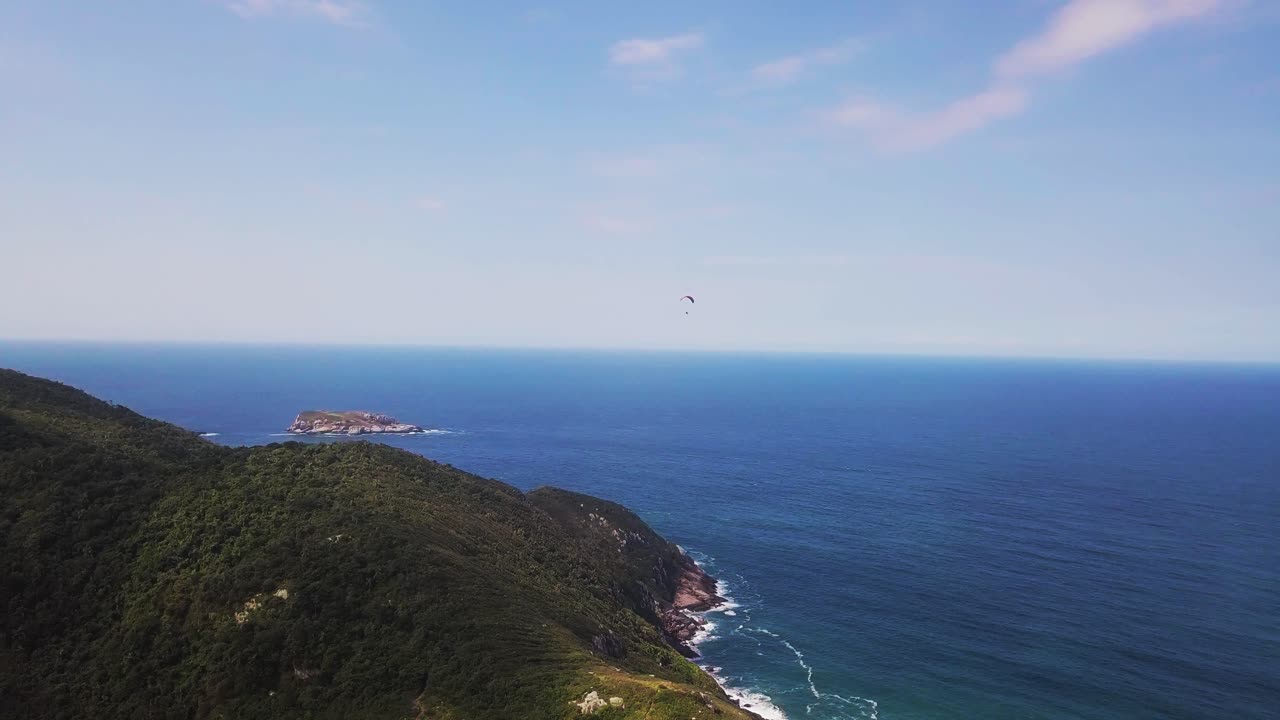 푸른 하늘이 있는 해변에서 파라모터 비행의 공중 추적 샷